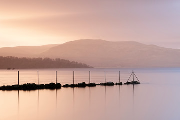 Sunset at Loch Lomond beautiful calm peaceful landscape scenic view reflection of jetty in water