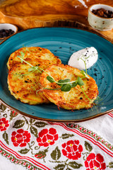 Close-up view of potato pancakes. Potato cake on a blue plate on the background of the national pattern