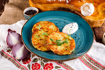 Close-up view of potato pancakes. Potato cake on a blue plate on the background of the national pattern