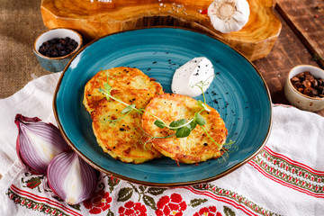 Close-up view of potato pancakes. Potato cake on a blue plate on the background of the national pattern