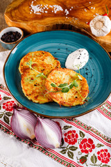 Close-up view of potato pancakes. Potato cake on a blue plate on the background of the national pattern