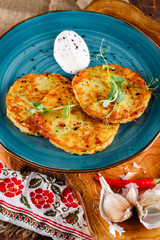 Close-up view of potato pancakes. Potato cake on a blue plate on the background of the national pattern