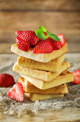 Waffeles with berries and mint leaf on a wood background