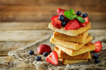 Waffeles with berries and mint leaf on a wood background
