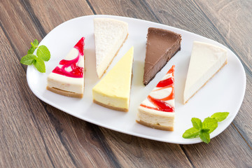 Slices of various cheese cakes on white plate. Sugar desserts, food concept 