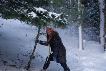 Female smiling and shaking a small snowy fir tree creating snowflakes