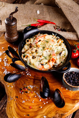 Tasty seafood in white sauce on a metal black plate.