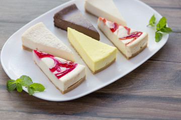 Slices of various cheese cakes on white plate. Sugar desserts, food concept 