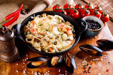 Tasty seafood in white sauce on a metal black plate.