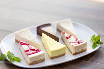 Slices of various cheese cakes on white plate. Sugar desserts, food concept 