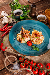 Pancakes with salmon, cream cheese and herbs. Bags tied with dill on a blue plate, next to the products for cooking,