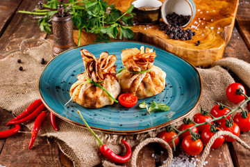 Pancakes with salmon, cream cheese and herbs. Bags tied with dill on a blue plate, next to the...