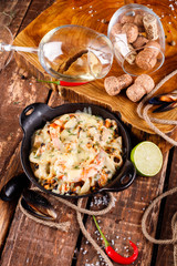 Tasty seafood in white sauce on a metal black plate.