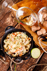 Tasty seafood in white sauce on a metal black plate.