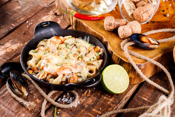 Tasty seafood in white sauce on a metal black plate.