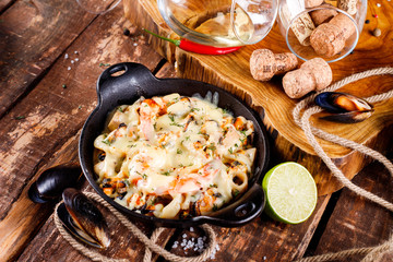 Tasty seafood in white sauce on a metal black plate.