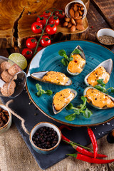 Large blue mussels on a blue plate on a wooden background, near the rope and products