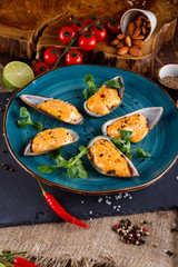 Large blue mussels on a blue plate on a wooden background, near the rope and products