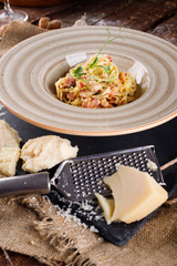 Pasta Carbonara with Parmesan on a white plate. Restaurant food at the wooden table