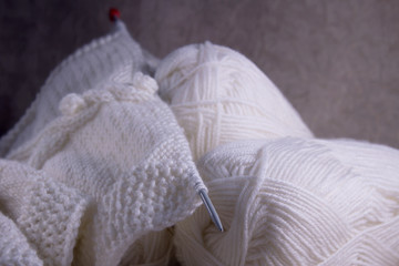 The process of knitting a white wool scarf for a woman. White yarn for knitting and knitting needle