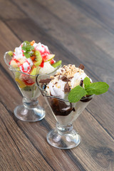 Fresh ice cream witn chocolate and fruits on wooden plate
