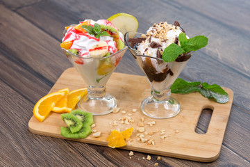 Fresh ice cream witn chocolate and fruits on wooden plate