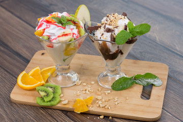 Fresh ice cream witn chocolate and fruits on wooden plate