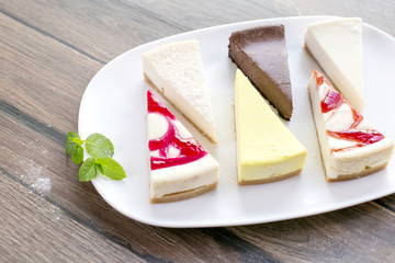 Pieces of various cheese cakes on plate in cafe. Food photo, sugar desserts concept
