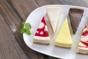 Pieces of various cheese cakes on plate in cafe. Food photo, sugar desserts concept