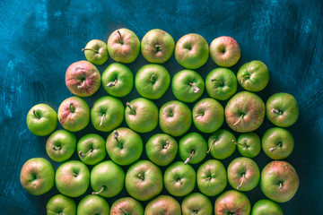 Fresh green organic apples bright light overhead colorful arrangement on blue background studio shot