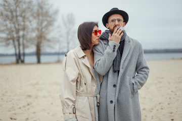 Young attractive girl and man walk along a deserted sandy beach. Romantic mood. Couple in love....