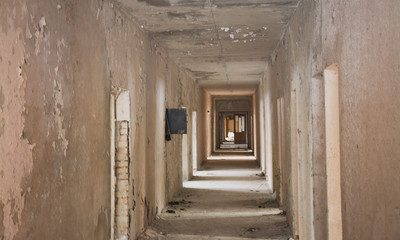 Fototapeta na wymiar The interior of an abandoned old building. A long corridor with entrances to rooms without doors.