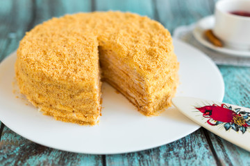 Honey cake on white plate on wooden table. Picture for a menu or a confectionery catalog