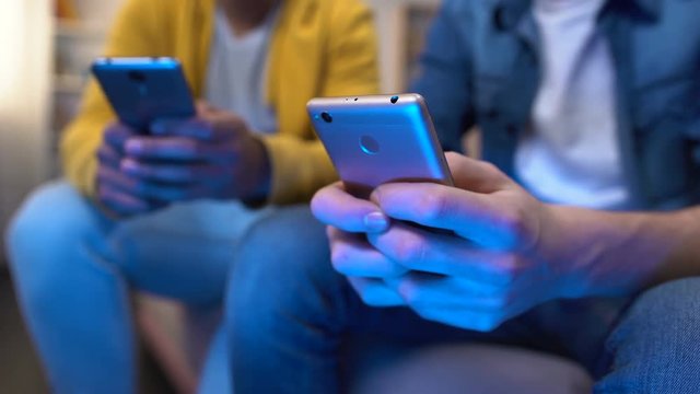 Male teenage friends winning multiplayer game on smartphones, gadget addiction