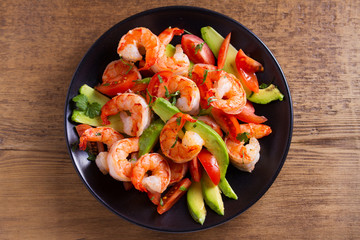 Shrimp, Avocado, Tomato and Cilantro Salad. Grilled prawns on black plate. View from above, top studio shot