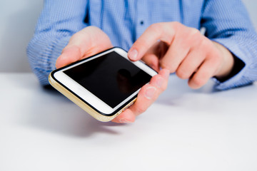 White telephone with empty, blank screen in the hand. The man shows a phone with a black display, ready to be filled with content. The concept of entering information on the phone. Using a smartphone.