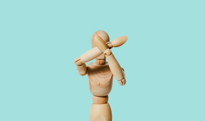 A wooden mannequin covers his face with his hands on a pastel background. The concept of reducing...