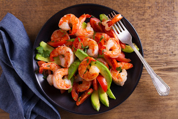 Shrimp, Avocado, Tomato and Cilantro Salad. Grilled prawns on black plate. View from above, top studio shot