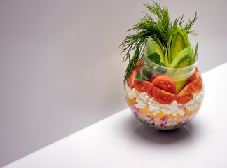 Salad of fresh vegetables with grain cottage cheese in a glass sphere with leek and dill. The concept of natural healthy food.