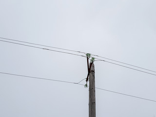 A pole with electrical wires. Wooden pole holding live wires