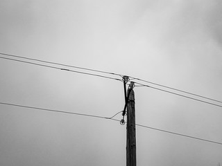 A pole with electrical wires. Wooden pole holding live wires