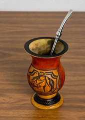 An empty gourd container (cuia) used to drink the Brazilian traditional mate-based  drink (chimarrao) on wooden table against white background, angle view
