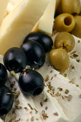 Exquisite festive snack closeup. Traditional Swiss, French, Italian, European delicacy for the holiday table, buffet, party. Olives, different types of cheese, nuts, spices on a plate.