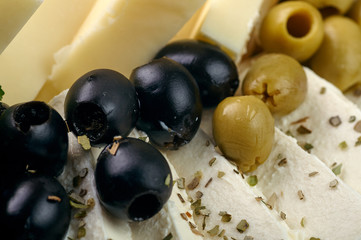 Exquisite festive snack closeup. Traditional Swiss, French, Italian, European delicacy for the holiday table, buffet, party. Olives, different types of cheese, nuts, spices on a plate.