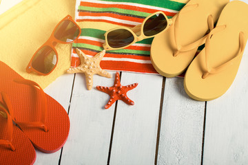 Flip flops, ball, tablet pc, seashell and starfish with tropical flowers on sandy beach