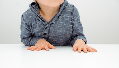 The nervousness of a little boy. The child nervously and impatiently holds his hands on the table....