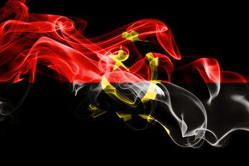 National flag of Angola made from colored smoke isolated on black background. Abstract silky wave...