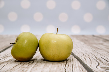 Two fresh green apples on wooden. Delicious apples lie on the table. The concept of providing vitamins along with fruits. Eating fruit on a daily basis.