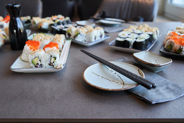 served different kind of sushi on white plates with blurry background ready to eat