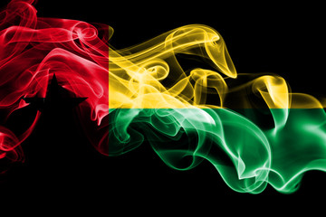 National flag of Guinea Bissau made from colored smoke isolated on black background. Abstract silky wave background.